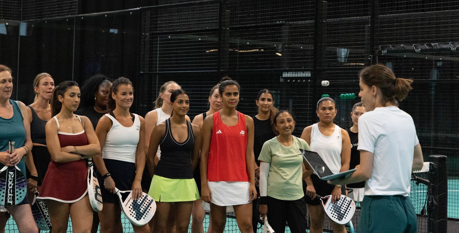 A group of women gathered together at an indoor padel court